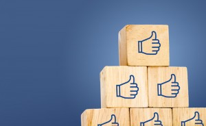 Thumb up icon on wood cube at dark blue background, leave space for adding text.